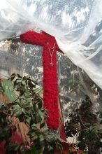 Una cruz with a rosary.  This display is completely protected from the weather by plastic.