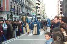 Un Nazareno drips candle wax for a young girl who is making a wax ball.